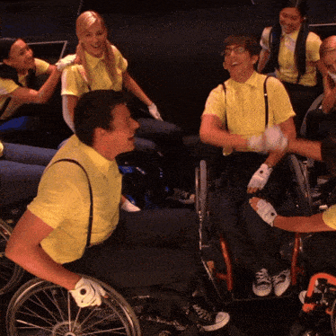 a group of people in yellow shirts are sitting in wheelchairs laughing
