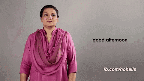 a woman in a pink dress is giving a sign that says good afternoon .
