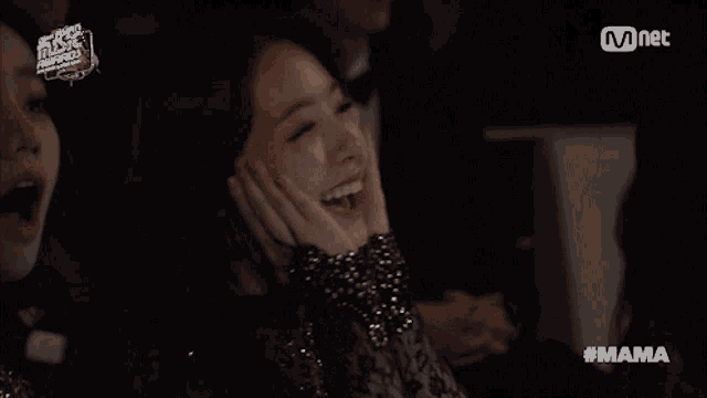 a woman laughs in front of a screen that says mama