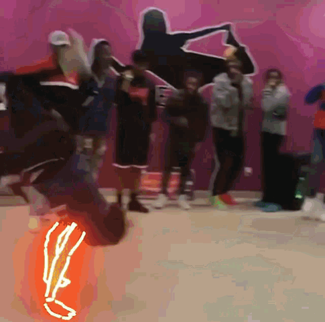 a group of people are dancing in front of a pink wall with a silhouette of a woman on it