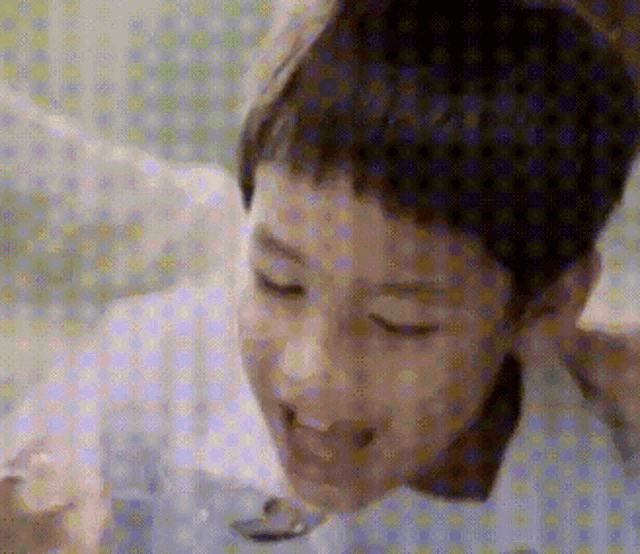 a young boy is eating something with a spoon and smiling