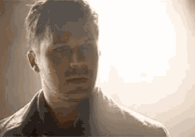 a close up of a man 's face in a dark room with a light shining on his face .