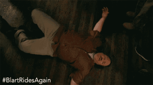 a man in a red shirt is laying on the floor with his arms outstretched .