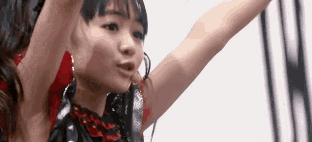 a woman in a black and red dress is dancing with her arms in the air .
