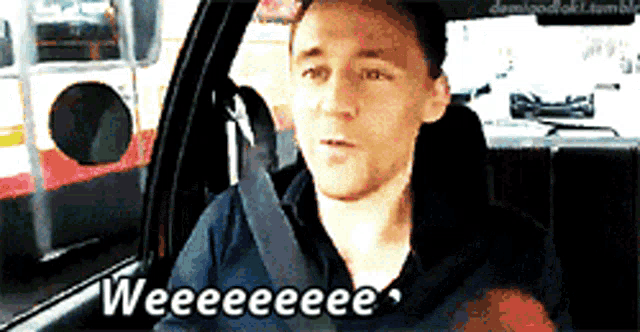 a man is sitting in a car with the words weeeee written on his face