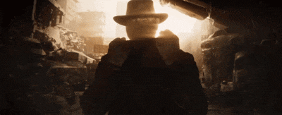 a man in a hat stands in a dark room