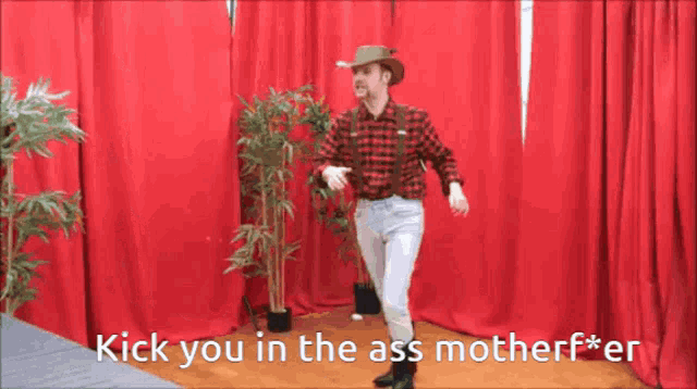 a man in a plaid shirt and suspenders is dancing in front of red curtains