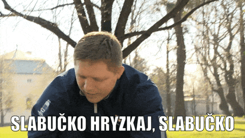 a man in a blue jacket with the words " slabucko hryzkaj slabucko " behind him
