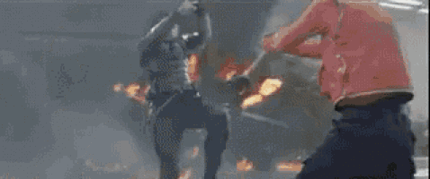 a group of people are standing next to each other in a room with a fire in the background .