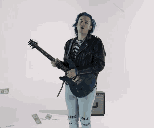 a man with blue hair is playing a guitar in a video