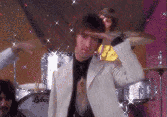 a man in a suit and tie is saluting in front of a drum set .