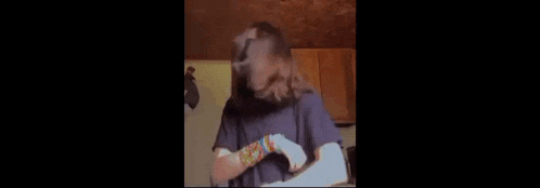 a woman wearing bracelets is standing in a kitchen .