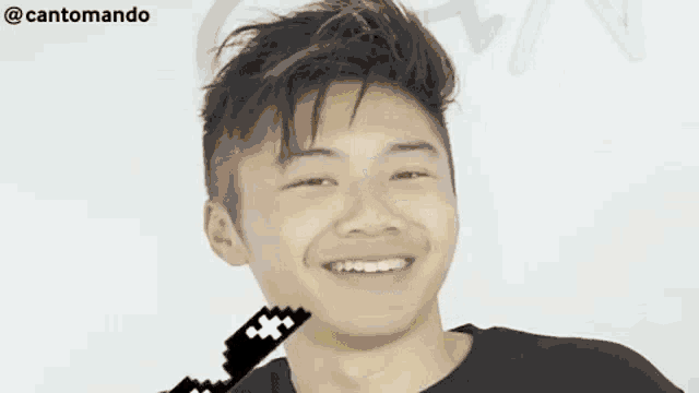 a young man is smiling and holding a pixelated key to his mouth .
