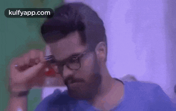 a man with a beard and glasses is holding a pair of scissors .