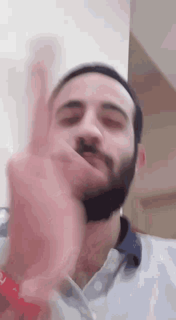 a man with a beard is giving the middle finger while wearing a polo shirt .