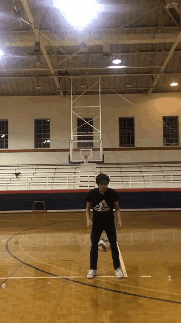 a man wearing an adidas shirt stands on a court