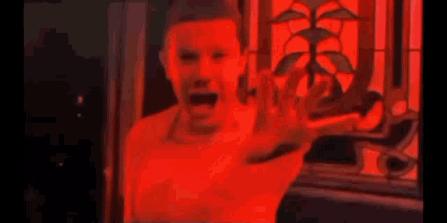 a person is screaming in front of a red window