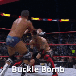 two men are wrestling in a ring and one of them is wearing a buckle bomb outfit .