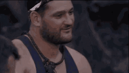 a man with a beard and a bandana on his head is eating food .