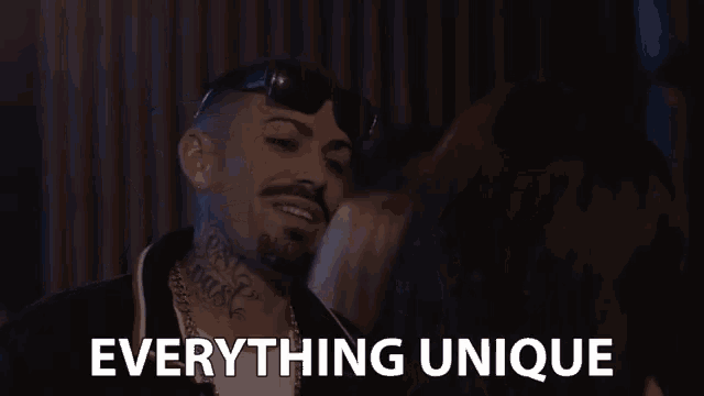 a man wearing sunglasses and a chain around his neck says everything unique .