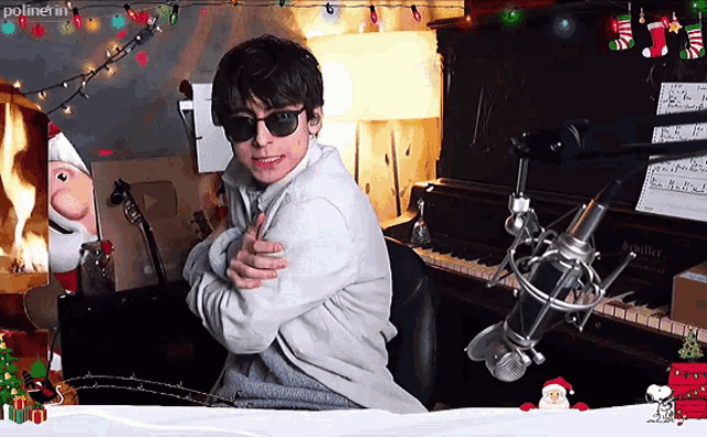 a man wearing sunglasses is sitting in front of a piano with a microphone in front of him