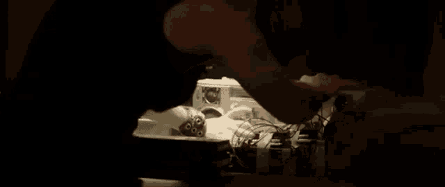 a man is working on a machine in a dark room with a lot of wires coming out of it .