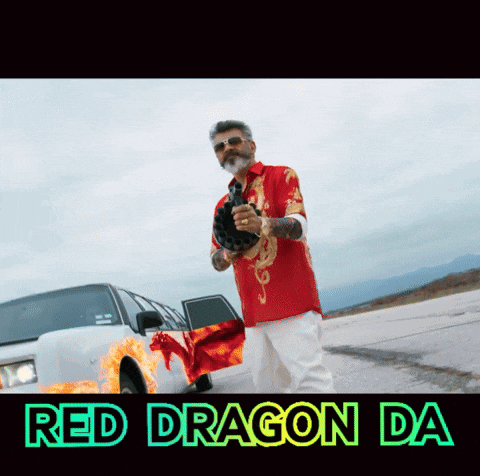 a man in a red shirt is holding a gun in front of a white car with a red dragon on the side