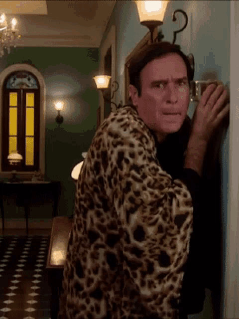 a man in a leopard print robe is peeking out from behind a door