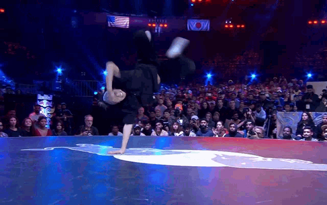 a man is doing a handstand in front of a crowd at a basketball game