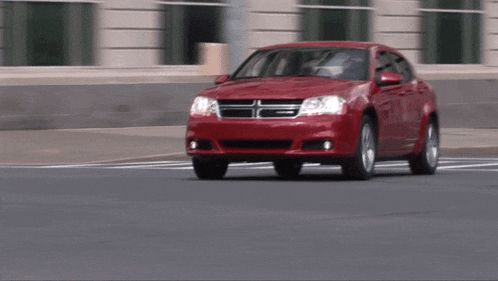 a red dodge car driving down a street