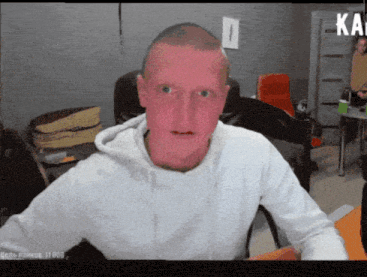 a man with a red face is sitting in front of a sign that says ka