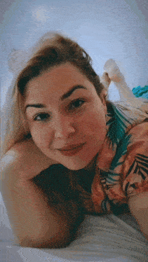 a woman is laying on her stomach on a bed and smiling for the camera