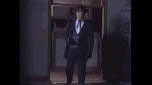 a man in a cowboy hat is holding a gun in his hand