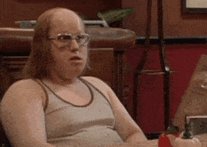 a bald man wearing glasses and a tank top is sitting at a table with a pumpkin .