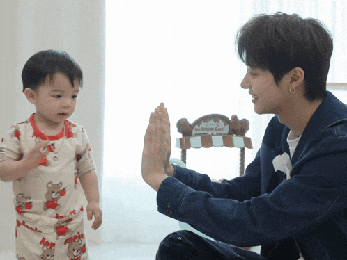 a man giving a baby a high five in front of a cotton candy cart