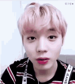 a close up of a young man with pink hair wearing a striped shirt and lipstick .