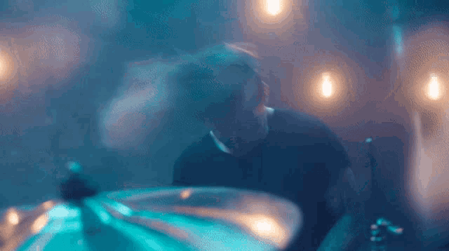 a man is playing drums in a dark room