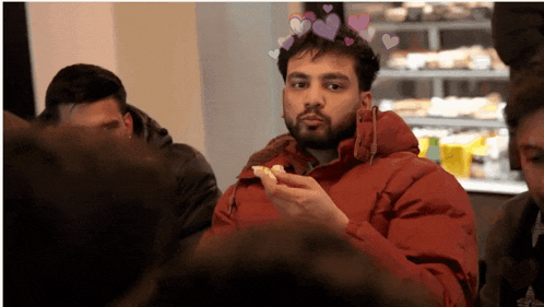a man in a red jacket is holding a piece of food in his hand