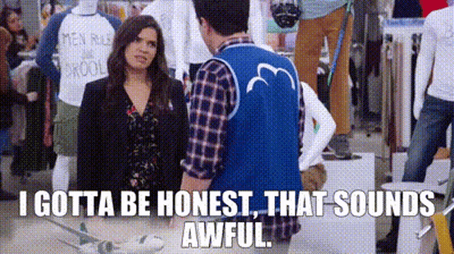 a man in a blue vest is standing next to a woman in a store and talking to her .