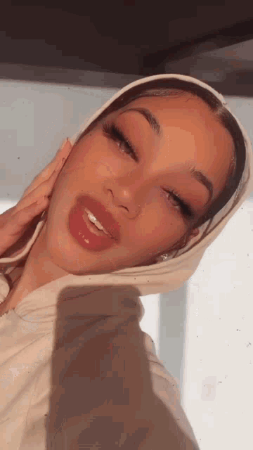 a woman wearing a white hoodie takes a selfie