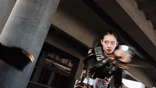 a woman in a black and gold costume is fighting a man