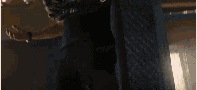 a man in a black shirt is standing in a dark room looking down