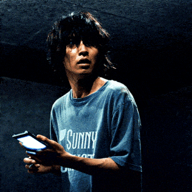 a man wearing a sunny shirt holds a cell phone