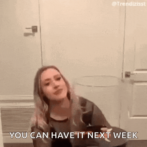 a woman is sitting on the floor in front of a door and saying `` you can have it next week '' .