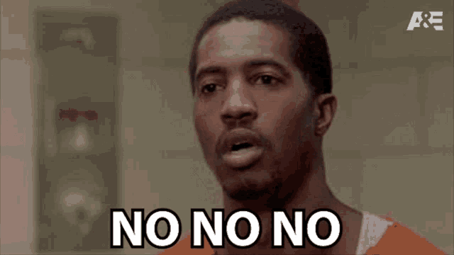 a man in a jail cell is making a funny face and saying no no no .