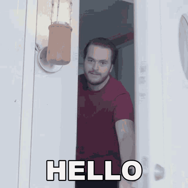 a man in a red shirt is standing in front of a door that says hello on it
