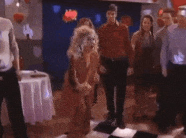 a group of people are dancing on a checkered floor in a club .