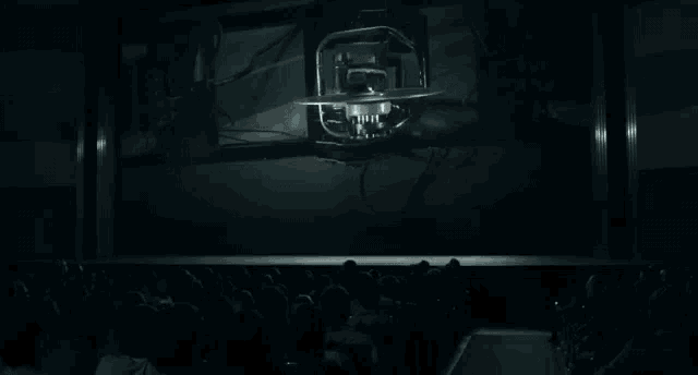 a crowd of people are sitting in front of a large screen watching a movie .