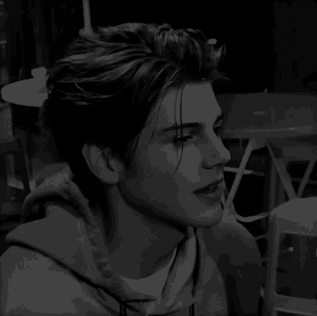 a black and white photo of a young man wearing a hoodie and a white shirt