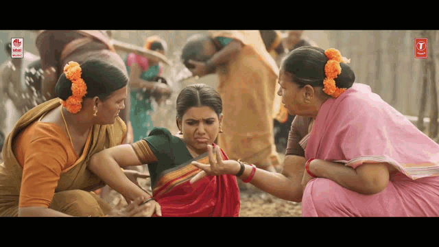 a woman in a red saree is being helped by a woman in a pink saree